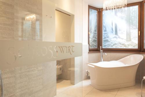 a bathroom with a tub and a sink and a window at Hotel Schlosswirt in Schenna