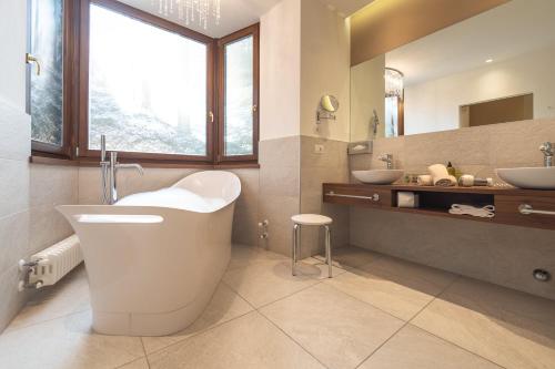 a bathroom with a large tub and two sinks at Hotel Schlosswirt in Schenna