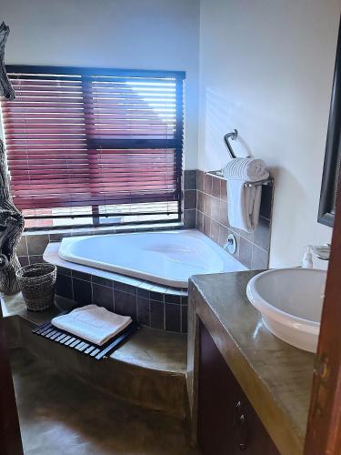a bathroom with a tub and a sink at 213 Zebula Golf Estate & Spa - 4 Bedroom Home in Mabula