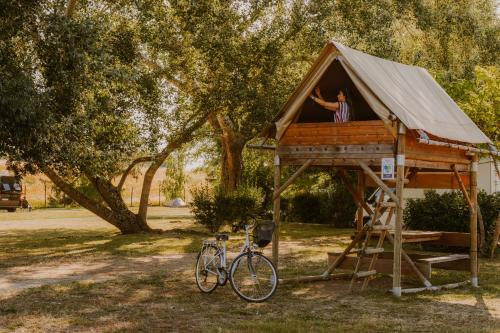 a person in a tree house with a bike at Camping Onlycamp Le Sabot in Azay-le-Rideau