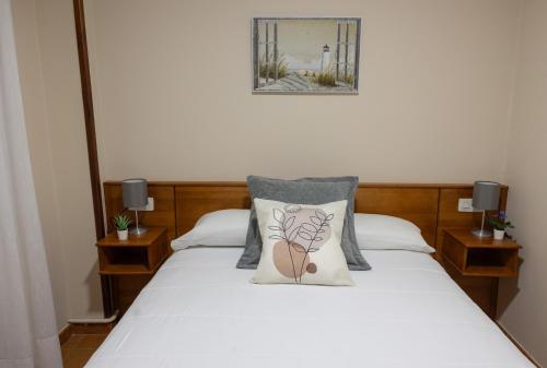 a bedroom with a white bed with two pillows at Pensión A Codeseira Melide in Melide