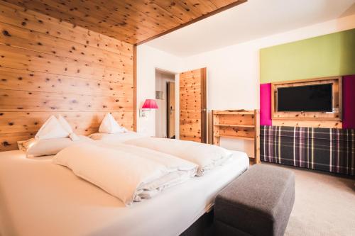 two beds in a bedroom with a wooden wall at Hotel Enzian - Adults Only in Obertauern