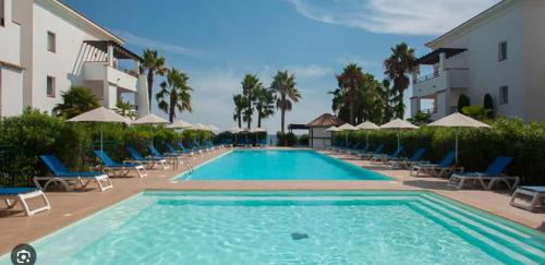 une grande piscine avec chaises et parasols dans l'établissement Appartement en Corse les pieds dans l'eau, à San-Nicolao