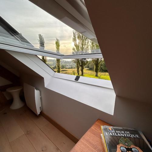 a room with a large window and a book on the floor at Gîtes et Spa en Normandie in Sainte-Marguerite-de-Viette