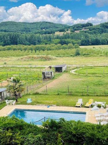 - une piscine dans un champ avec des chaises et une maison dans l'établissement Maison Les Écuries-Piscine-Castelnaud, à Castelnaud-la-Chapelle