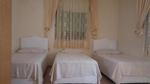 two beds in a room with white sheets at Maison d'hôtes afoulki tafraout in Tafraoute