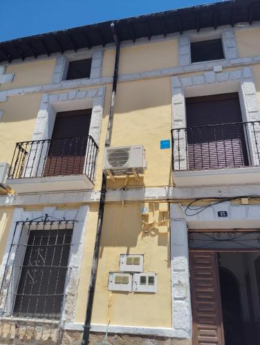 a yellow building with two windows and an air conditioner at Buhardilla barranquilla in Poyales del Hoyo