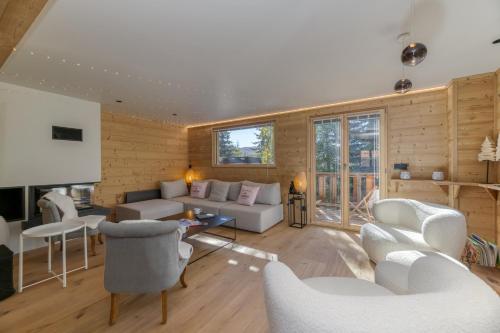 a living room with white furniture and wooden walls at Homency - Chalet La Pavicha in L'Alpe-d'Huez