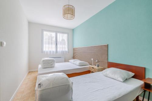 une chambre avec deux lits et une fenêtre dans l'établissement L’Évasion Atlantique - Appt à 5 min de la plage, à Saint-Jean-de-Monts
