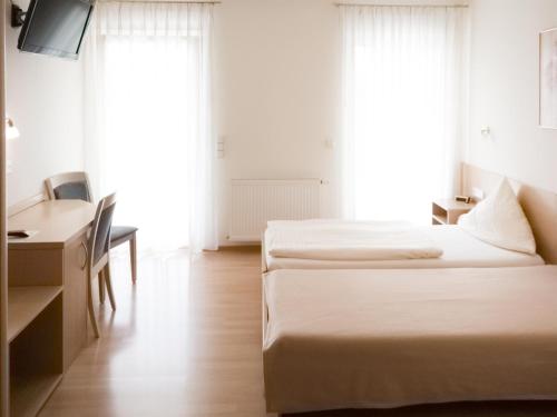 a hotel room with two beds and a desk and a desk at Pension Zum Bahnhof in Mörlheim