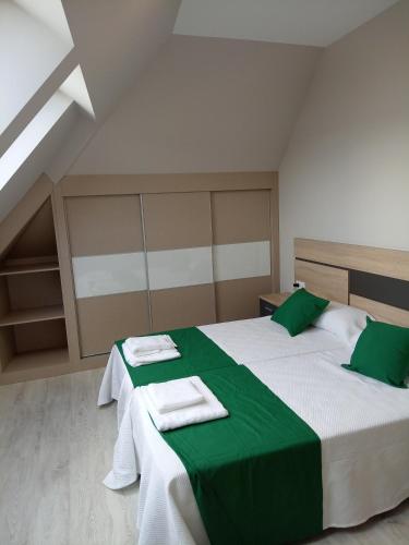 a bedroom with two beds with green and white sheets at Apartamentos Mar y Playa in Moaña
