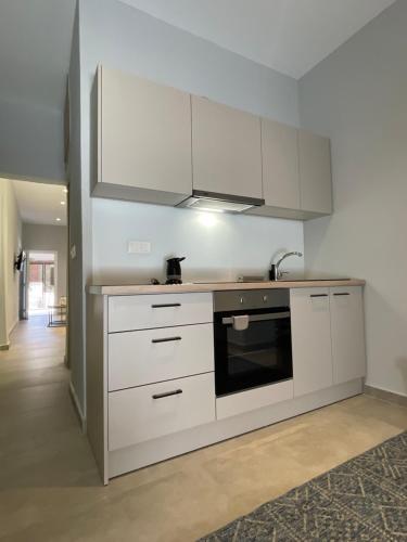 a kitchen with white cabinets and a sink at Karamelas Vacation House in Nea Kalikratia