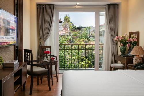 a bedroom with a bed and a desk and a balcony at The West Hotel & Spa in Hanoi