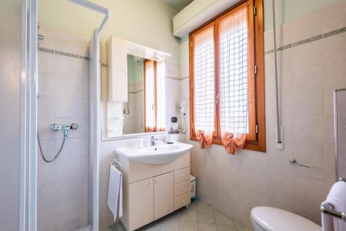 a white bathroom with a sink and a mirror at Tenuta Fornacelle La Rosa in San Gimignano