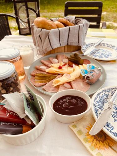 a table with plates of food and a basket of bread at Téesz Vendégház in Zalaháshágy