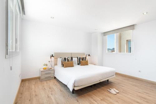 a white bedroom with a bed and a window at The Corner Apartments by Aspasios in Barcelona