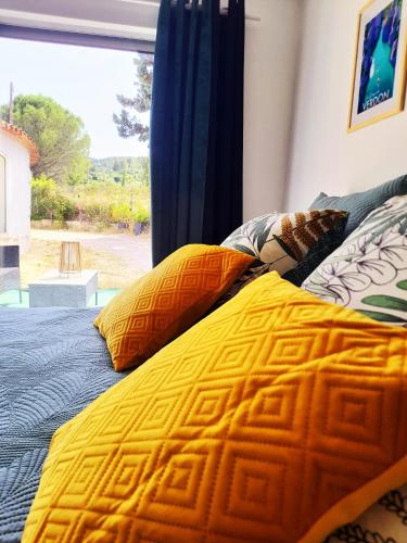 - un lit avec une couette jaune et une fenêtre dans l'établissement Logement La Belle Provence, au Beausset