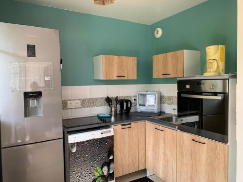 - une cuisine avec des placards en bois et un four micro-ondes dans l'établissement Paris Saclay Versailles à 20 minutes, à Nozay