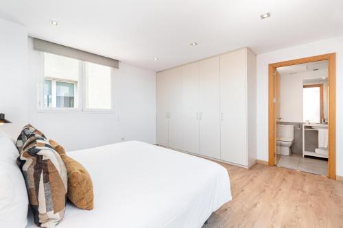 a white bedroom with a bed and a bathroom at The Corner Apartments by Aspasios in Barcelona