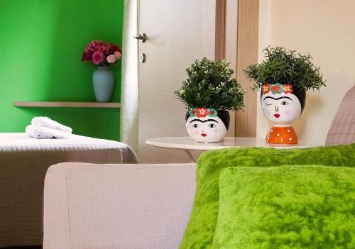 two vases with faces on them sitting on a table with plants at Le Residenze degli Ulivi in Campofilone