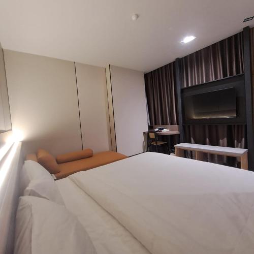 a bedroom with a large white bed and a television at Urban Inn, Myra Meranti in Cyberjaya