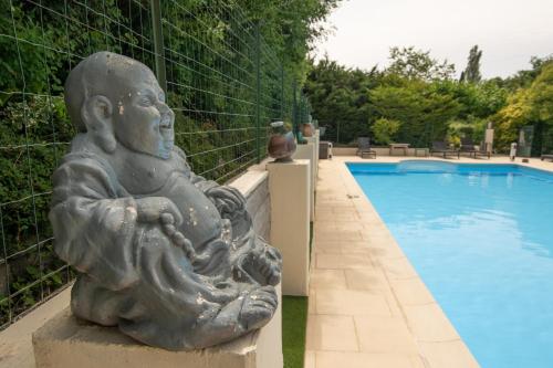 une statue assise à côté d'une piscine dans l'établissement Maison De Vacances Avec Piscine, à Gras