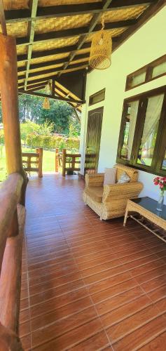 a living room with a couch and a wooden floor at Sumatra Cheeky Monkeys Villa, Trekking and Tours in Bukit Lawang