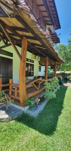 a house with a wooden roof and some grass at Sumatra Cheeky Monkeys Villa, Trekking and Tours in Bukit Lawang
