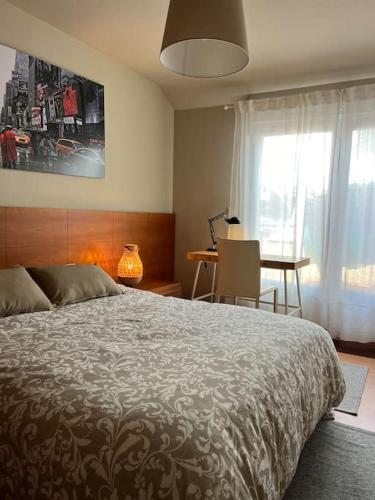 a bedroom with a bed and a desk and a window at Apartamento centro Porto do Son in Porto do Son