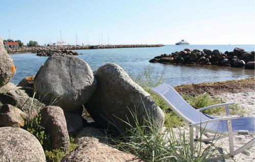 a white chair sitting on a beach next to some rocks at Holiday Home Spodsbjergvej I in Spodsbjerg
