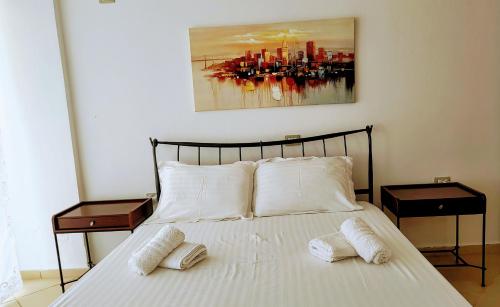 a bed with white pillows and a painting on the wall at Polyxeni Apartments & Rooms in Qeparo