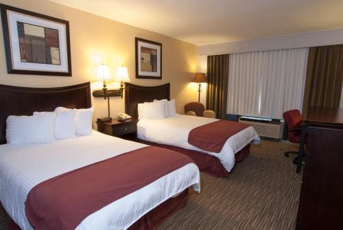a hotel room with two beds and a television at Lamplighter Inn & Suites Pittsburg in Pittsburg