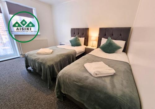 a room with two beds with green pillows at Aisiki Stays Apartments at Harwoods Road, Multiple 2-Bedroom, Pet-Friendly Flat, King or Twin or Double Beds, with Free Wi-Fi and Parking Space in Watford