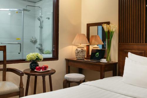 a hotel room with a bed and a desk with a computer at The West Hotel & Spa in Hanoi