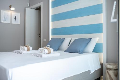 a white bed with blue and white pillows on it at Mare Villas Pescoluse- Design Apartment in Marina di Pescoluse