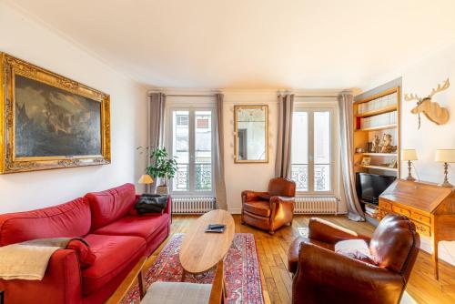 un salon avec un canapé rouge et une table dans l'établissement GuestReady - central apartment at Les Invalides, à Paris