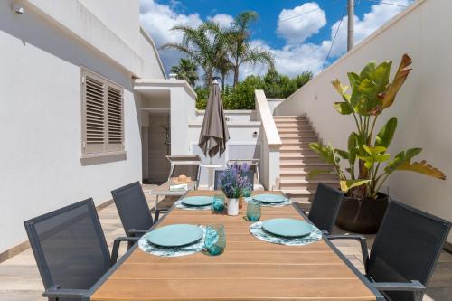 a wooden table and chairs on a patio at Mare Villas Pescoluse- Design Apartment in Marina di Pescoluse