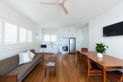 uma sala de estar com um sofá e uma mesa de jantar em The Beach Shack Byron Bay em Byron Bay