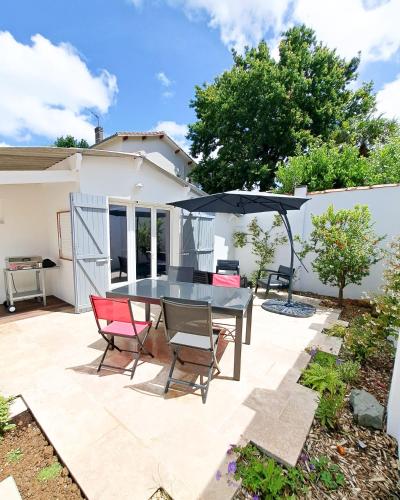 un patio avec une table, des chaises et un parasol dans l'établissement Mariella - MAISON FAMILIALE, WIFI, 500m de la plage, à Royan