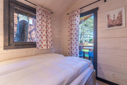 a small bedroom with a bed and a window at Domki - Sosnowy Las in Pobierowo