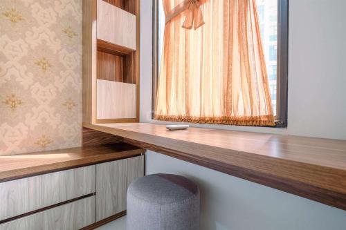 a room with a window with a bench and a stool at Good Deal and Relaxing 2BR Transpark Cibubur Apartment By Travelio in Depok