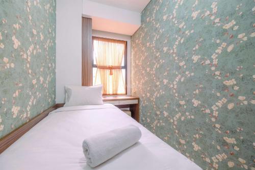 a bedroom with a white bed and a window at Good Deal and Relaxing 2BR Transpark Cibubur Apartment By Travelio in Depok