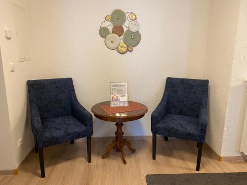 two chairs and a table and a clock on the wall at Ferienwohnungen Clara in Arnstadt