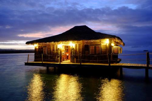 a house on a dock in the water at night at Ratua Private Island Resort in Aimbuei Bay