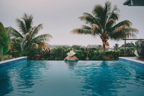 a woman in a hat sitting in a swimming pool at Avaiki Nui Villa in Avarua