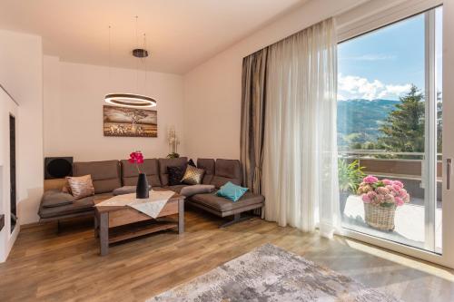 a living room with a couch and a large window at Aparthotel AlpTirol in Kaltenbach
