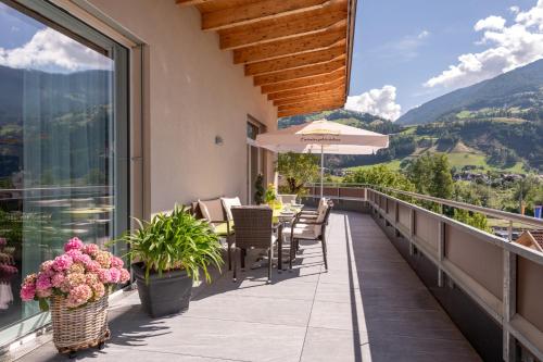 a balcony with tables and chairs and a view of mountains at Aparthotel AlpTirol in Kaltenbach