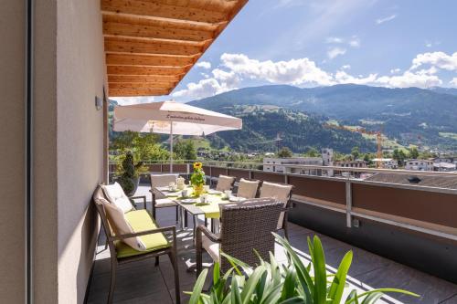 a balcony with a table with chairs and an umbrella at Aparthotel AlpTirol in Kaltenbach
