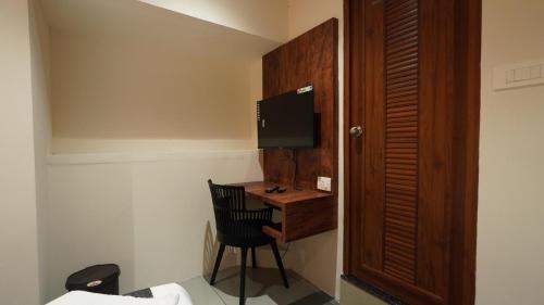 a room with a desk with a chair and a television at Hotel Hive Inn - Kozhikode in Kozhikode
