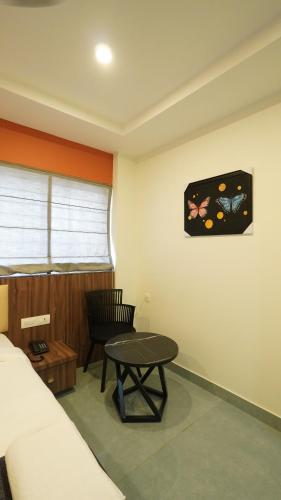 a room with a bed and a table and a chair at Hotel Hive Inn - Kozhikode in Kozhikode